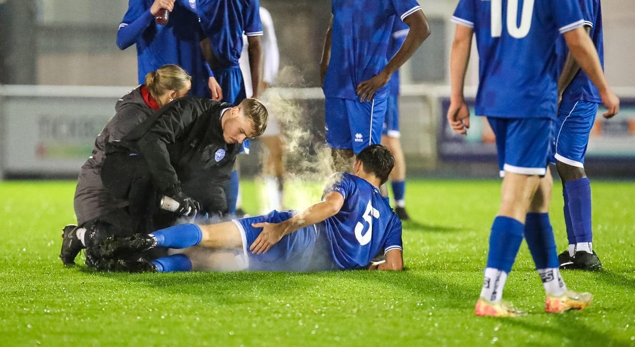 Professional sports therapist performing manual therapy treatment on athlete in clinical setting
